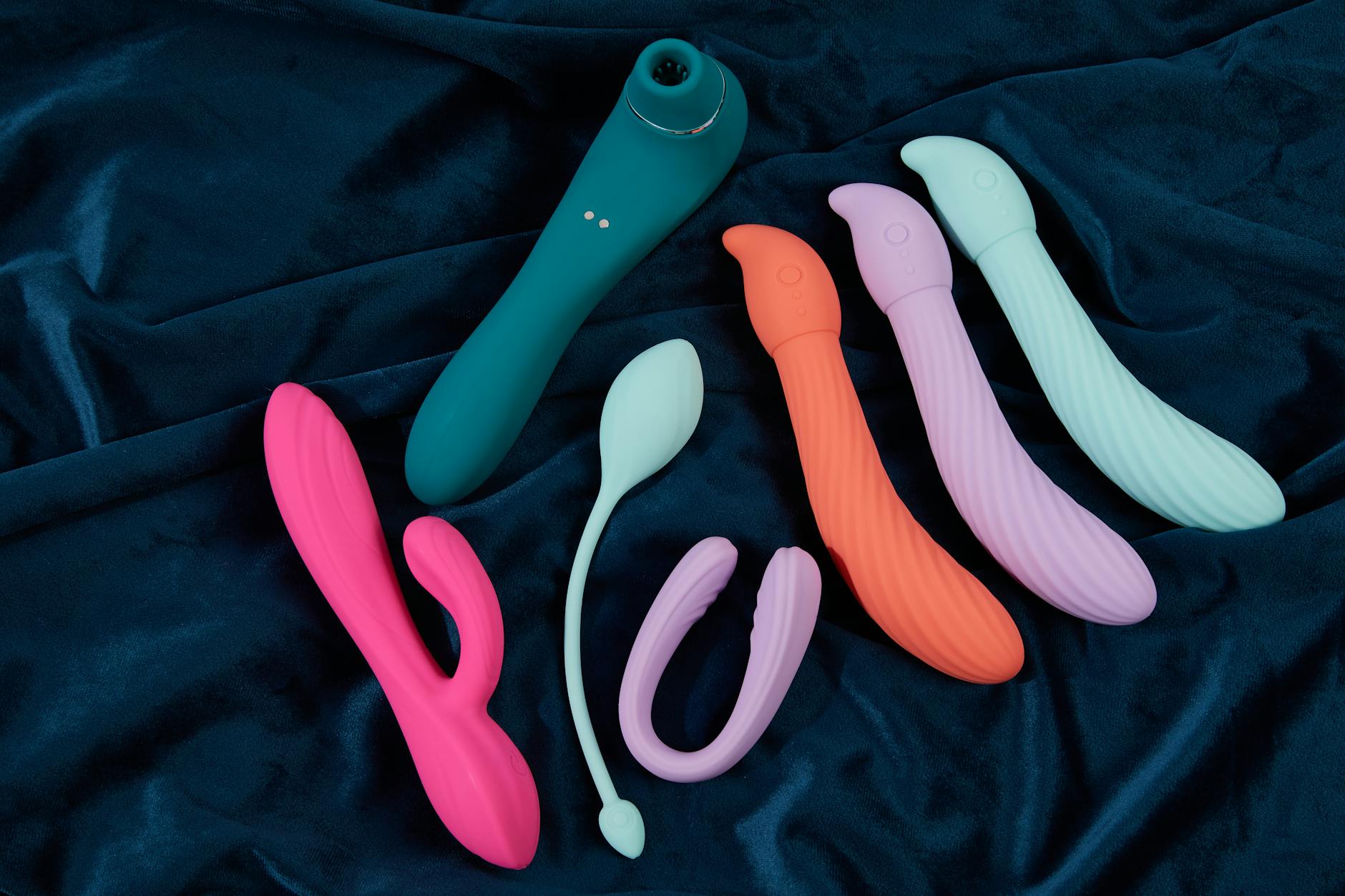 Vibrant collection of silicone clitoral vibrators on dark fabric, showcasing modern adult toy design