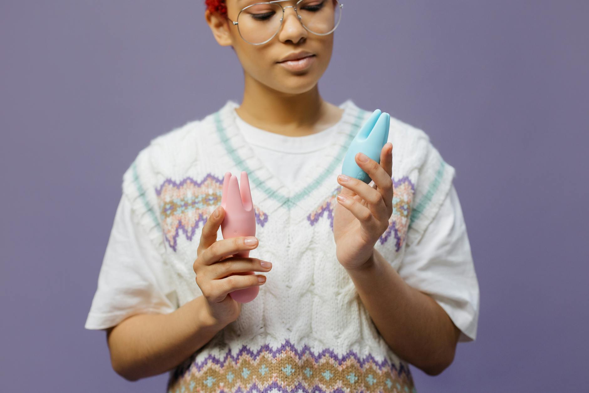 A woman holding a blue silicone vibrator, contemplative and thoughtful about her pleasure choices.